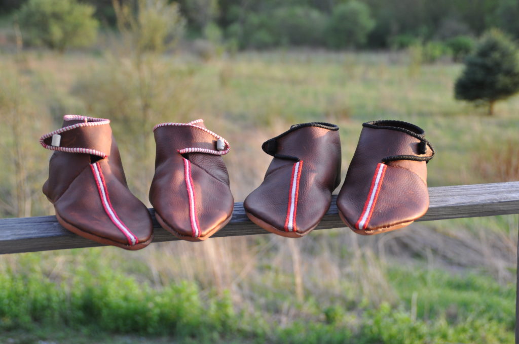 2 pairs of embroidered shoes on a fence rail