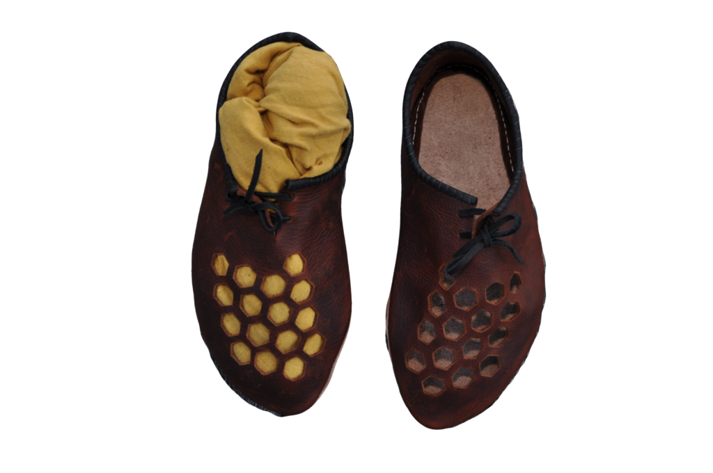 a pair of brown leather shoes whose vamps have hexagons punched out